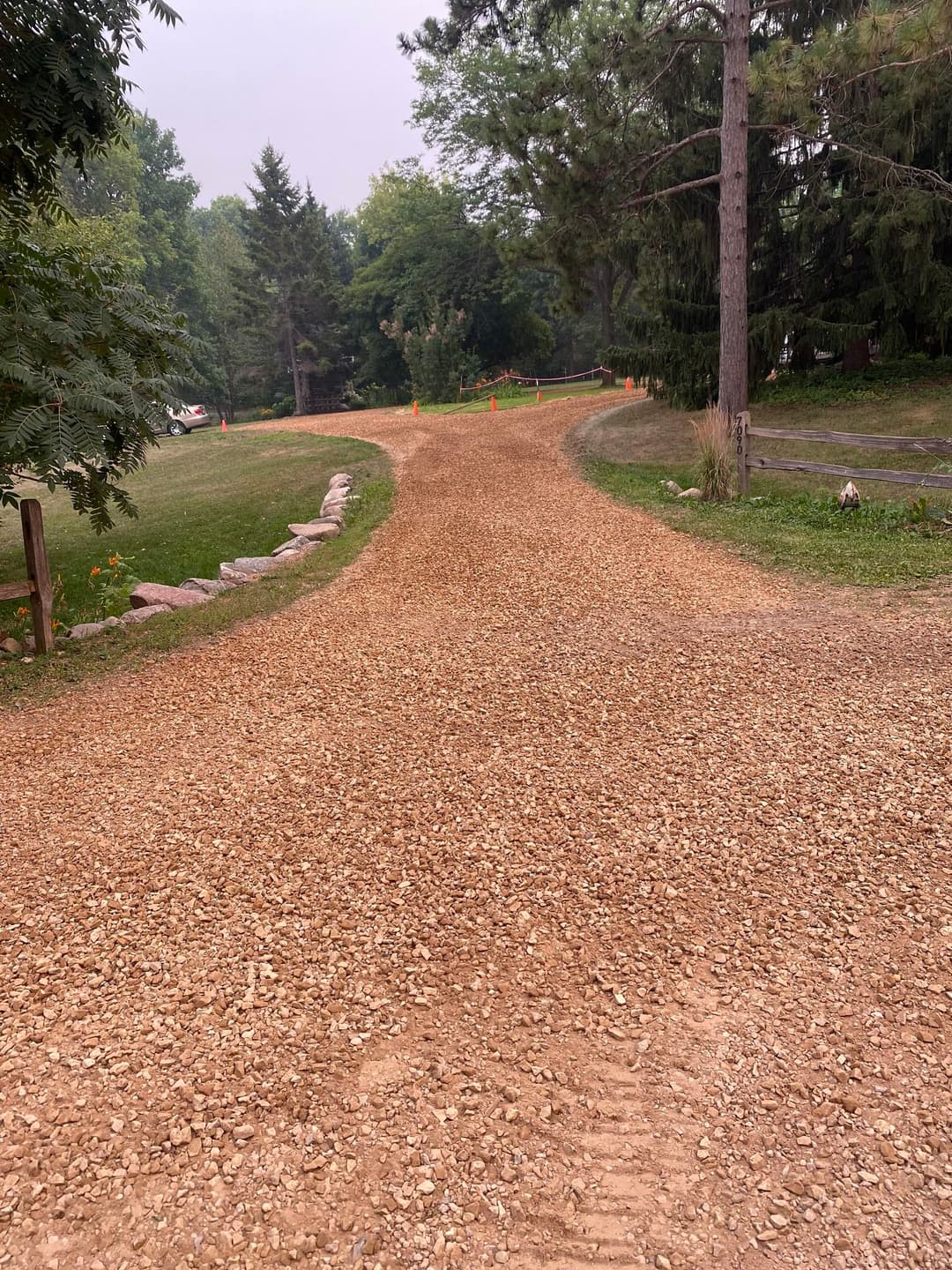 Gravel pathway winding through a wooded area, surrounded by greenery and trees.